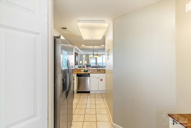 8499 Gulf Blvd Unit 1303, Navarre Beach, FL 32566 - kitchen featuring stainless steel appliances, a sink, a chandelier, white cabinets, and light tile patterned floors