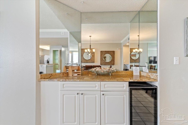 8499 Gulf Blvd Unit 1303, Navarre Beach, FL 32566 - kitchen featuring beverage cooler, a chandelier, ornamental molding, white cabinetry, and hanging light fixtures
