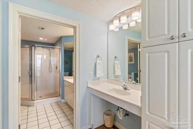 8499 Gulf Blvd Unit 1303, Navarre Beach, FL 32566 - bathroom featuring a textured ceiling, a stall shower, tile patterned flooring, and a sink