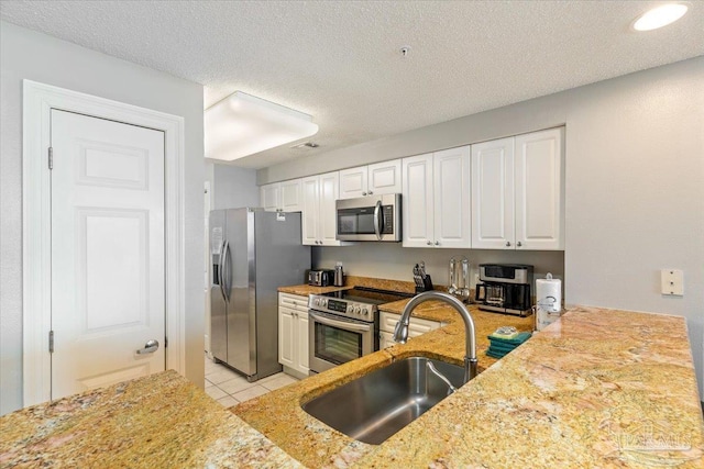 8499 Gulf Blvd Unit 1303, Navarre Beach, FL 32566 - kitchen with stainless steel appliances, a sink, white cabinets, light tile patterned floors, and a textured ceiling