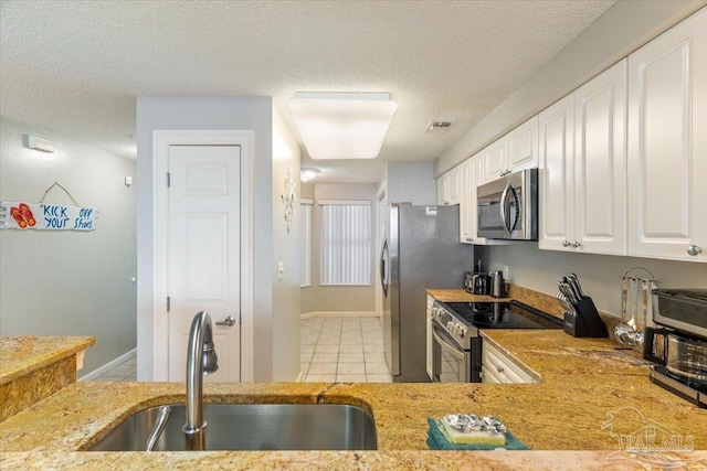 8499 Gulf Blvd Unit 1303, Navarre Beach, FL 32566 - kitchen featuring stainless steel appliances, a sink, white cabinetry, a textured ceiling, and light tile patterned floors