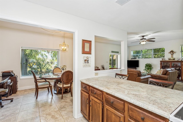 kitchen with ceiling fan with notable chandelier, a wealth of natural light, light tile patterned floors, and decorative light fixtures