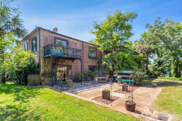 rear view of property with a balcony, a patio, and a lawn