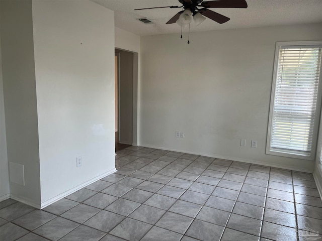 tiled spare room with a textured ceiling and ceiling fan