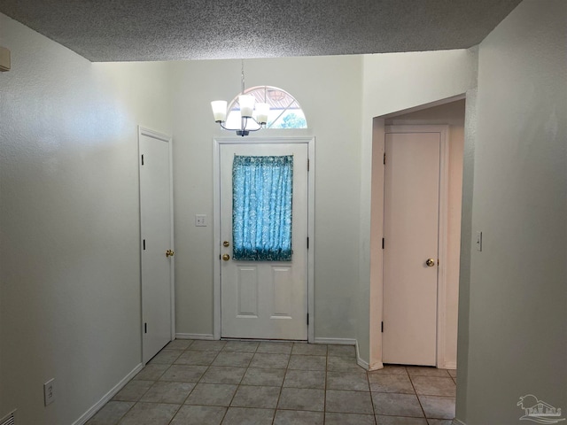 tiled entryway featuring a textured ceiling and a chandelier