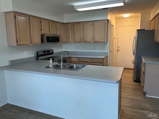 kitchen featuring light brown cabinets, kitchen peninsula, stainless steel appliances, hardwood / wood-style flooring, and sink