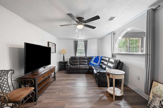 living room with a textured ceiling, wood-type flooring, and ceiling fan