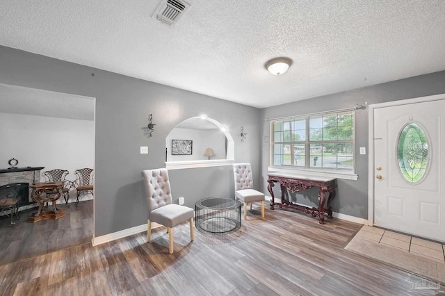 entryway with a fireplace, wood-type flooring, and a textured ceiling