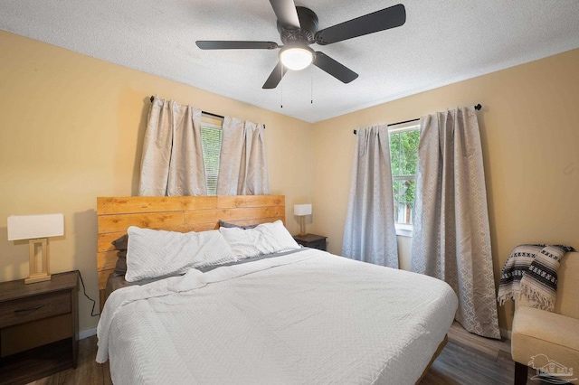 bedroom with ceiling fan, dark hardwood / wood-style flooring, and a textured ceiling