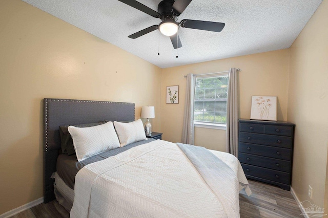 bedroom with hardwood / wood-style flooring, a textured ceiling, and ceiling fan