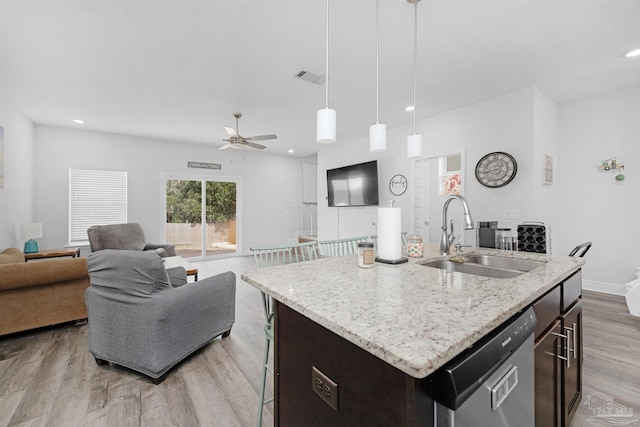 kitchen featuring dishwasher, decorative light fixtures, sink, a center island with sink, and dark brown cabinets