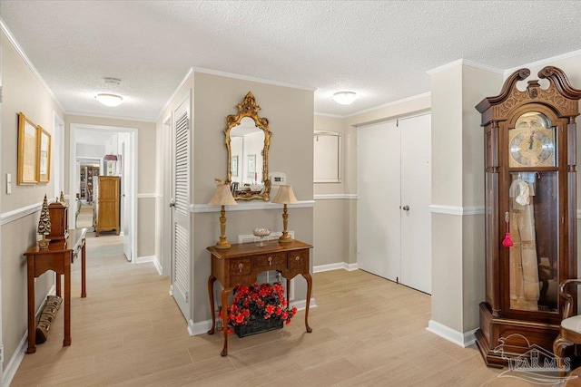 hallway with a textured ceiling, light hardwood / wood-style flooring, and crown molding