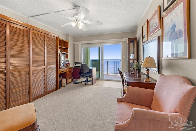 carpeted office with a textured ceiling, crown molding, ceiling fan, and a water view