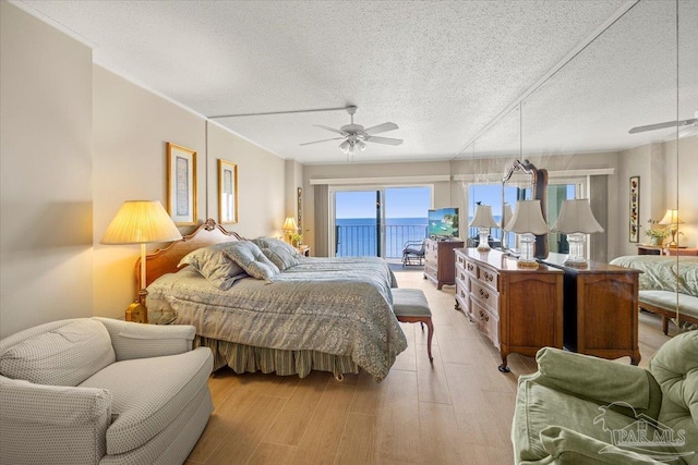 bedroom featuring light wood-type flooring, ceiling fan, access to exterior, and a textured ceiling