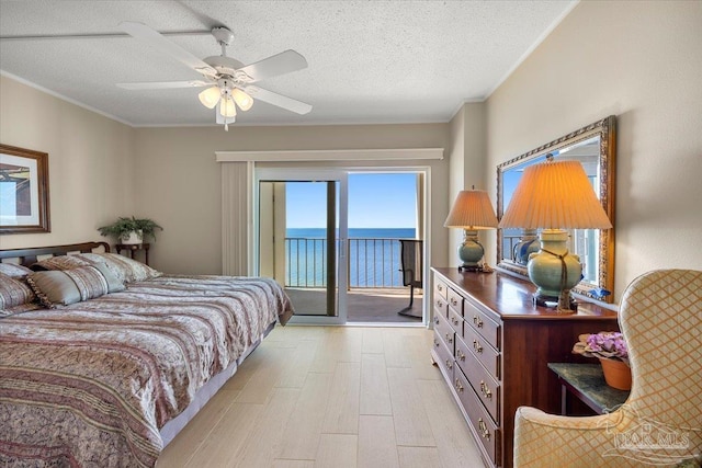 bedroom featuring a textured ceiling, a water view, ceiling fan, and access to outside