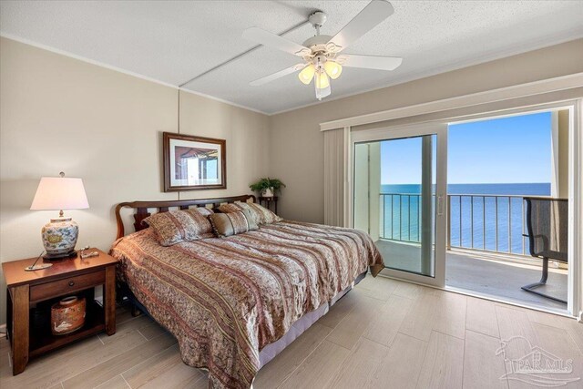 bedroom with light hardwood / wood-style floors, ceiling fan, a water view, and access to outside