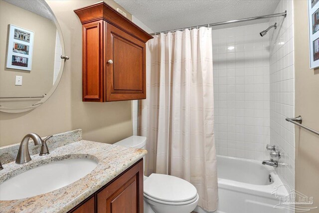 full bathroom featuring shower / bathtub combination with curtain, vanity, toilet, and a textured ceiling