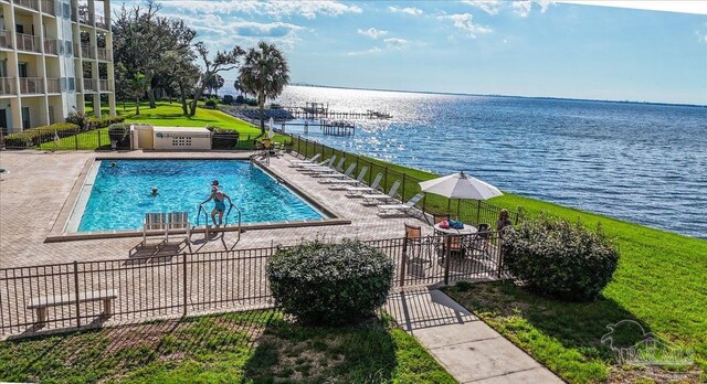 view of swimming pool with a yard, a patio, and a water view