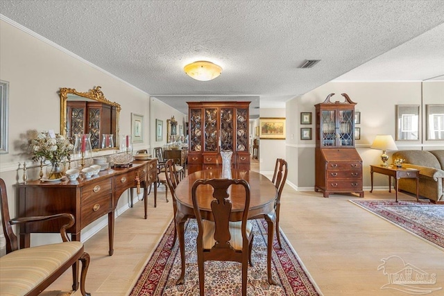 dining area featuring a textured ceiling, crown molding, and light hardwood / wood-style floors