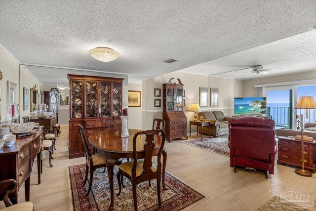 dining room with a textured ceiling, a healthy amount of sunlight, and light hardwood / wood-style floors