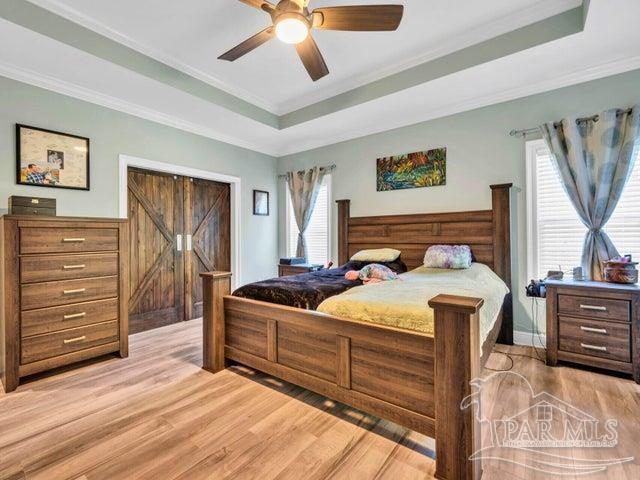 1516 Cadence Loop, Cantonment, FL 32533 - bedroom with a tray ceiling, light wood-style flooring, crown molding, and a ceiling fan