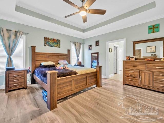 1516 Cadence Loop, Cantonment, FL 32533 - bedroom with a raised ceiling, ornamental molding, multiple windows, and light wood-type flooring