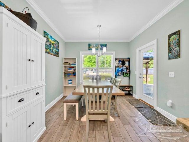 1516 Cadence Loop, Cantonment, FL 32533 - dining room featuring light wood-type flooring, crown molding, baseboards, and a chandelier