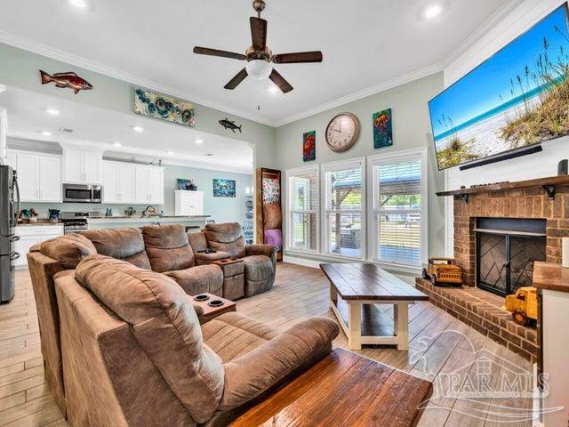 1516 Cadence Loop, Cantonment, FL 32533 - living room featuring crown molding, ceiling fan, light wood-type flooring, a brick fireplace, and recessed lighting