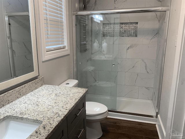 bathroom featuring toilet, vanity, an enclosed shower, and hardwood / wood-style flooring