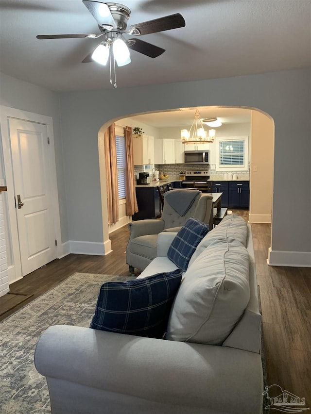 living room with dark hardwood / wood-style flooring and ceiling fan with notable chandelier