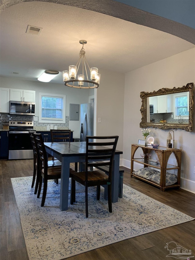 dining space featuring an inviting chandelier and dark wood-type flooring