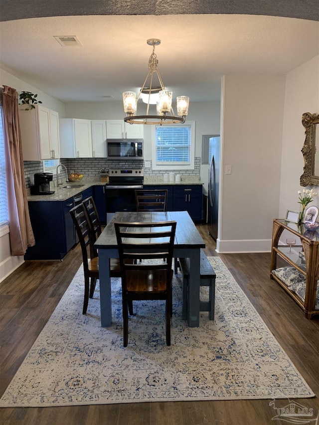 dining space featuring dark hardwood / wood-style flooring, sink, and a notable chandelier