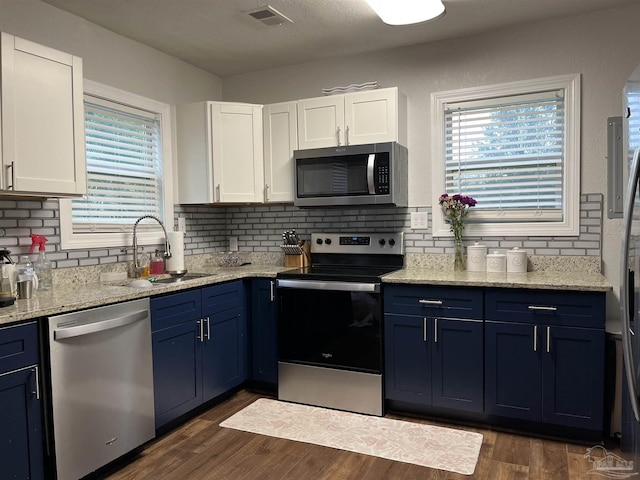 kitchen with appliances with stainless steel finishes, backsplash, sink, blue cabinetry, and white cabinets