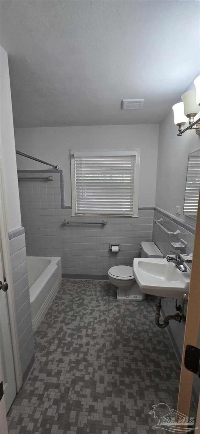 381 Euclid St, Pensacola, FL 32503 - bathroom featuring tile walls, wainscoting, and a chandelier