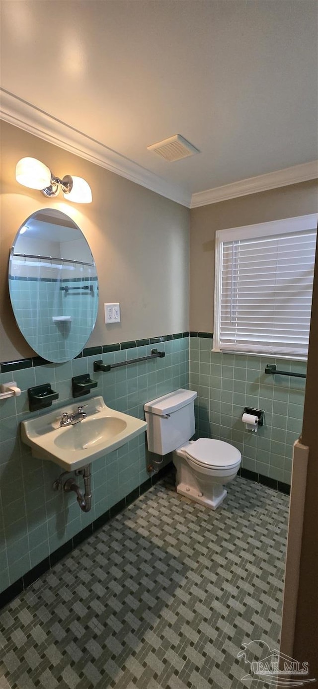 381 Euclid St, Pensacola, FL 32503 - bathroom with tile walls, crown molding, and wainscoting