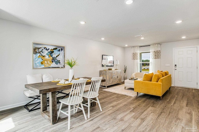 dining area with a textured ceiling and light wood-type flooring