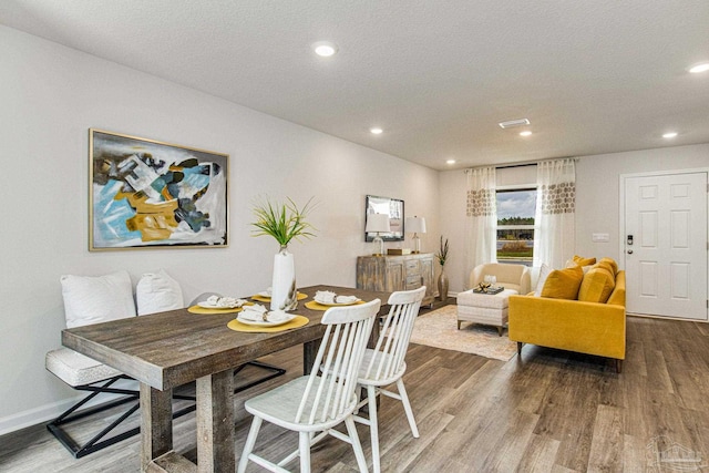 dining space with wood-type flooring and a textured ceiling