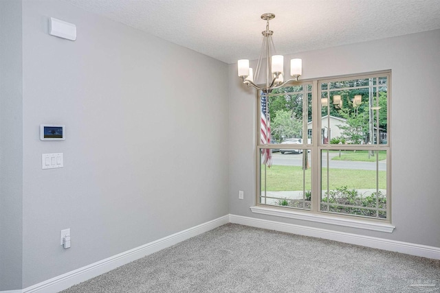 spare room with carpet, a notable chandelier, and a textured ceiling