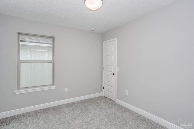 carpeted empty room featuring a textured ceiling