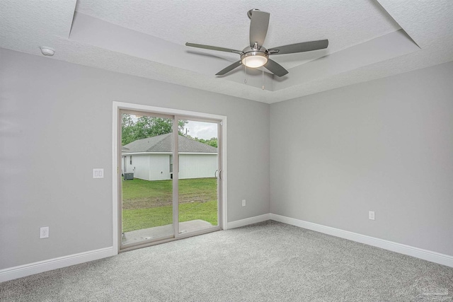 carpeted spare room with ceiling fan, a textured ceiling, and a tray ceiling