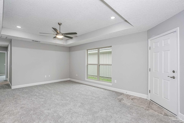 carpeted empty room with ceiling fan, a tray ceiling, and a textured ceiling