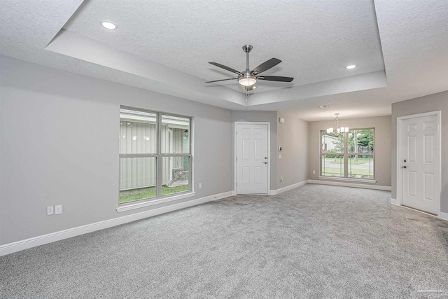 spare room featuring ceiling fan with notable chandelier, a raised ceiling, a textured ceiling, and carpet