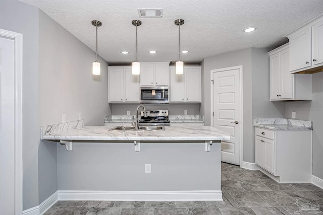 kitchen with hanging light fixtures, kitchen peninsula, white cabinets, and appliances with stainless steel finishes