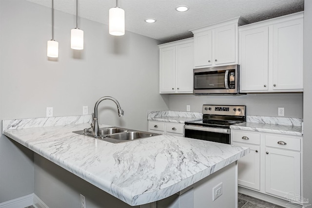 kitchen featuring sink, stainless steel appliances, white cabinets, decorative light fixtures, and kitchen peninsula