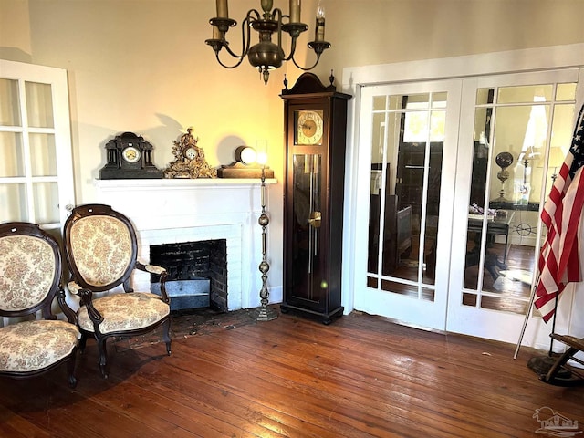 living area featuring dark wood-type flooring, a fireplace, french doors, and a chandelier