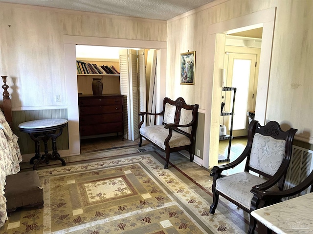 living area with ornamental molding, a textured ceiling, and wooden walls