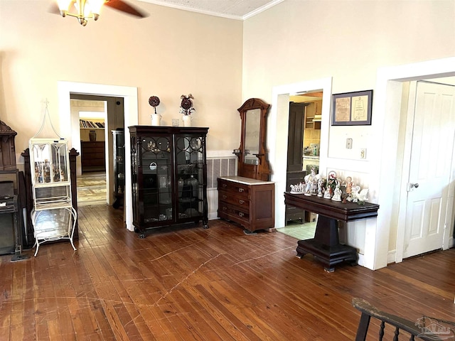 sitting room featuring a high ceiling, crown molding, and dark wood-type flooring