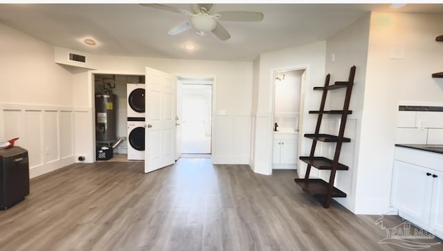 interior space featuring stacked washing maching and dryer, a wainscoted wall, ceiling fan, and visible vents