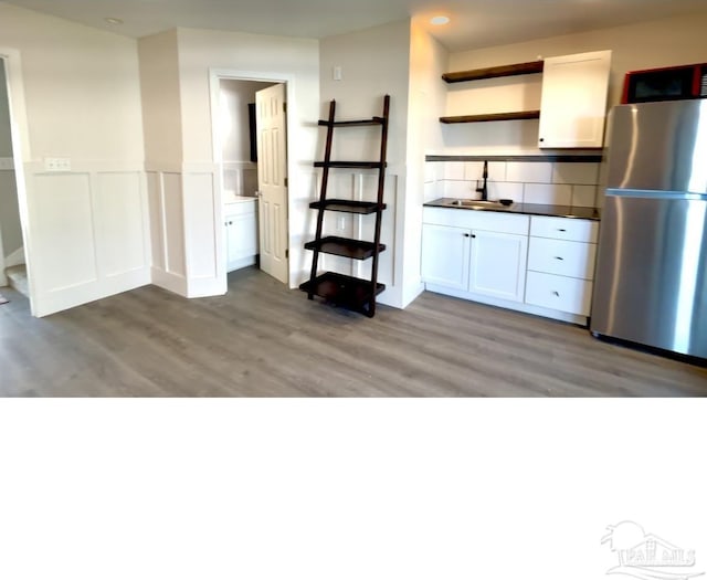 kitchen featuring a sink, freestanding refrigerator, open shelves, and light wood-style flooring