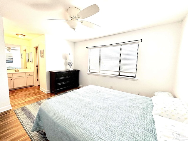bedroom featuring baseboards, a ceiling fan, ensuite bathroom, and wood finished floors